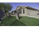 Artificial turf backyard with a tree stump, chairs, and a fenced area at 147 S Los Cielos Ln, Casa Grande, AZ 85194