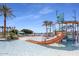 Resort-style pool with a water slide and bucket feature, surrounded by palm trees and lounge chairs at 18187 W Wind Song Ave, Goodyear, AZ 85338