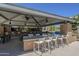 Outdoor kitchen and dining area with grills and seating at 18439 W Wind Song Ave, Goodyear, AZ 85338