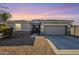 Single-story home with a gray exterior, two-car garage, and desert landscaping at 18439 W Wind Song Ave, Goodyear, AZ 85338