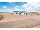 New construction white stucco home featuring a three-car garage and desert landscape at 25505 W Brookhart Way, Wittmann, AZ 85361
