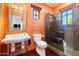 Small bathroom with stand-alone sink, shower, and orange walls at 8375 E Via Dona Rd, Scottsdale, AZ 85266