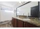 Double vanity bathroom with granite countertops and large mirror at 11553 N 76Th Dr, Peoria, AZ 85345