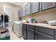 Functional laundry room with gray cabinets and a double sink at 18904 W Mercer Ln, Surprise, AZ 85388