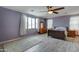 Bedroom featuring wooden floors, ceiling fan, curtains, large windows, and traditional furnishings at 20552 W Carlton Mnr, Buckeye, AZ 85396