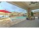 Covered patio with an inviting pool, string lights, hot tub, and a table with a red umbrella at 20552 W Carlton Mnr, Buckeye, AZ 85396