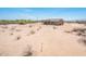 A beige single-story home with a covered patio sits on a large, desert landscape lot at 21916 W Duane Ln, Wittmann, AZ 85361