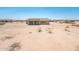 A beige single-story home with a covered patio sits on a large, desert landscape lot at 21916 W Duane Ln, Wittmann, AZ 85361