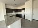 Modern kitchen featuring granite counters, dark cabinets, tile floors, and stainless steel double sinks at 21916 W Duane Ln, Wittmann, AZ 85361