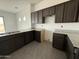 Well-lit kitchen with dark cabinets, granite countertops, stainless steel sink, and gray tile flooring at 21916 W Duane Ln, Wittmann, AZ 85361