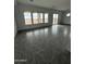 A living room with gray, rectangular tile flooring and three large windows at 25519 W Brookhart Way, Wittmann, AZ 85361