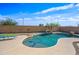 Backyard swimming pool features rock waterfall, lounge chairs and is surrounded by desert landscaping at 3383 E Santa Fe Ln, Gilbert, AZ 85297