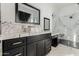 Elegant bathroom with marble shower, double vanity, and black cabinets at 34150 W Corleone Dr, Maricopa, AZ 85138