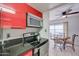 Sleek kitchen with red cabinets, black countertops, and a view into the dining area at 3416 N 44Th St # 35, Phoenix, AZ 85018