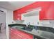 Modern kitchen featuring red cabinetry, granite countertops, and a stylish sink at 3416 N 44Th St # 35, Phoenix, AZ 85018