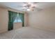 Spacious bedroom with green curtains, ceiling fan, and carpeted floors at 4805 W Saguaro Park Ln, Glendale, AZ 85310