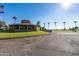 Exterior view of the clubhouse with palm trees and a golf course in the background at 10714 W Saratoga Cir, Sun City, AZ 85351