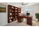 Home office with built-in shelves, desk, and ceiling fan at 15857 W Yavapai St, Goodyear, AZ 85338