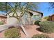 Tan house with a two-car garage and mature tree in front at 1828 W Owens Way, Anthem, AZ 85086