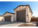 View of a modern home's three-car garage with gray doors and landscaped surroundings at 22901 E Quintero Rd, Queen Creek, AZ 85142