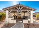 Outdoor kitchen under a stylish pergola, complete with a built-in grill, bar seating, and an outdoor television at 22901 E Quintero Rd, Queen Creek, AZ 85142