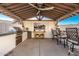 Inviting outdoor kitchen with a built-in grill, a TV, bar seating, and a ceiling fan for comfort at 22901 E Quintero Rd, Queen Creek, AZ 85142