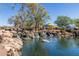 Community park featuring a pond with waterfalls, lush greenery, and a colorful playground in the background at 3703 W Mccauley Ct, Phoenix, AZ 85086