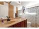 Bathroom with single sink, wood cabinets, and patterned shower curtain at 43579 W Arizona Ave, Maricopa, AZ 85138