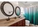 Bathroom with double sinks, teal shower curtain, and decorative mirrors at 43579 W Arizona Ave, Maricopa, AZ 85138