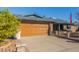 Front view of a single story home with a wooden garage door and mature trees at 5210 W Ironwood Dr, Glendale, AZ 85302