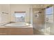 A well-lit bathroom featuring a glass shower and a tiled garden tub next to a window at 638 W Nido Ave, Mesa, AZ 85210