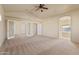 A large main bedroom with neutral carpet, a ceiling fan, and doors to the outside at 638 W Nido Ave, Mesa, AZ 85210