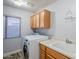 Laundry room with wood cabinets, a washer, dryer, and utility sink at 23619 N 21St St, Phoenix, AZ 85024