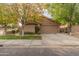 Tan house with a two-car garage and mature trees in the front yard at 5025 E Waltann Ln, Scottsdale, AZ 85254