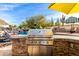 Built-in outdoor kitchen with stainless steel appliances and a yellow umbrella at 9535 E Mclellan Rd, Mesa, AZ 85207