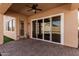 Cozy covered patio with brick pavers, ceiling fan, and sliding glass doors to the interior at 13550 W Port Au Prince Ln, Surprise, AZ 85379