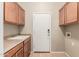Well-lit laundry room includes utility sink, storage cabinets, and neutral color palette at 13550 W Port Au Prince Ln, Surprise, AZ 85379