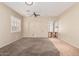 Open living room with neutral walls, carpet, shuttered windows, ceiling fan, and arched doorway at 13550 W Port Au Prince Ln, Surprise, AZ 85379