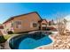 Backyard oasis with a refreshing pool, artificial grass, and rock landscaping at 13550 W Port Au Prince Ln, Surprise, AZ 85379