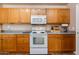 View of kitchen with wood cabinets and white appliances at 5731 W Aster Dr, Glendale, AZ 85304