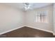 Bright bedroom with dark wood floors, ceiling fan, and window shutters at 18487 N 111Th Dr, Surprise, AZ 85378