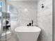 Bathroom with a large white tub, stylish mirror, and marble-patterned tile walls at 19531 N 69Th Ave, Glendale, AZ 85308