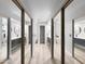 A hallway leading to a white-walled bathroom with a large mirror and vanity at 19531 N 69Th Ave, Glendale, AZ 85308