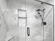 Modern shower with black fixtures, glass door, and white marble-patterned tile walls at 19531 N 69Th Ave, Glendale, AZ 85308