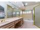 Well-lit bathroom featuring dual sinks, a large mirror, and a separate tiled shower with gold trim at 25440 S Flame Tree Dr, Sun Lakes, AZ 85248