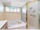 Bathroom featuring a tub with gold fixtures and a glass-enclosed shower, complemented by a sunny window at 25440 S Flame Tree Dr, Sun Lakes, AZ 85248