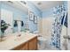 Bathroom features a vanity with a sink, toilet, and shower/tub combination with a floral shower curtain at 13022 W Surrey Ave, El Mirage, AZ 85335