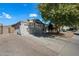 Exterior view of a well-maintained home with a 2-car garage and a mature shade tree in the front yard at 13022 W Surrey Ave, El Mirage, AZ 85335
