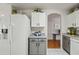 Bright kitchen featuring a white refrigerator, gray cabinets, and an arched doorway that offers a functional cooking space at 13022 W Surrey Ave, El Mirage, AZ 85335