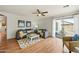 Comfortable living room featuring hardwood floors, ceiling fan, and a sliding glass door that leads to the backyard at 13022 W Surrey Ave, El Mirage, AZ 85335